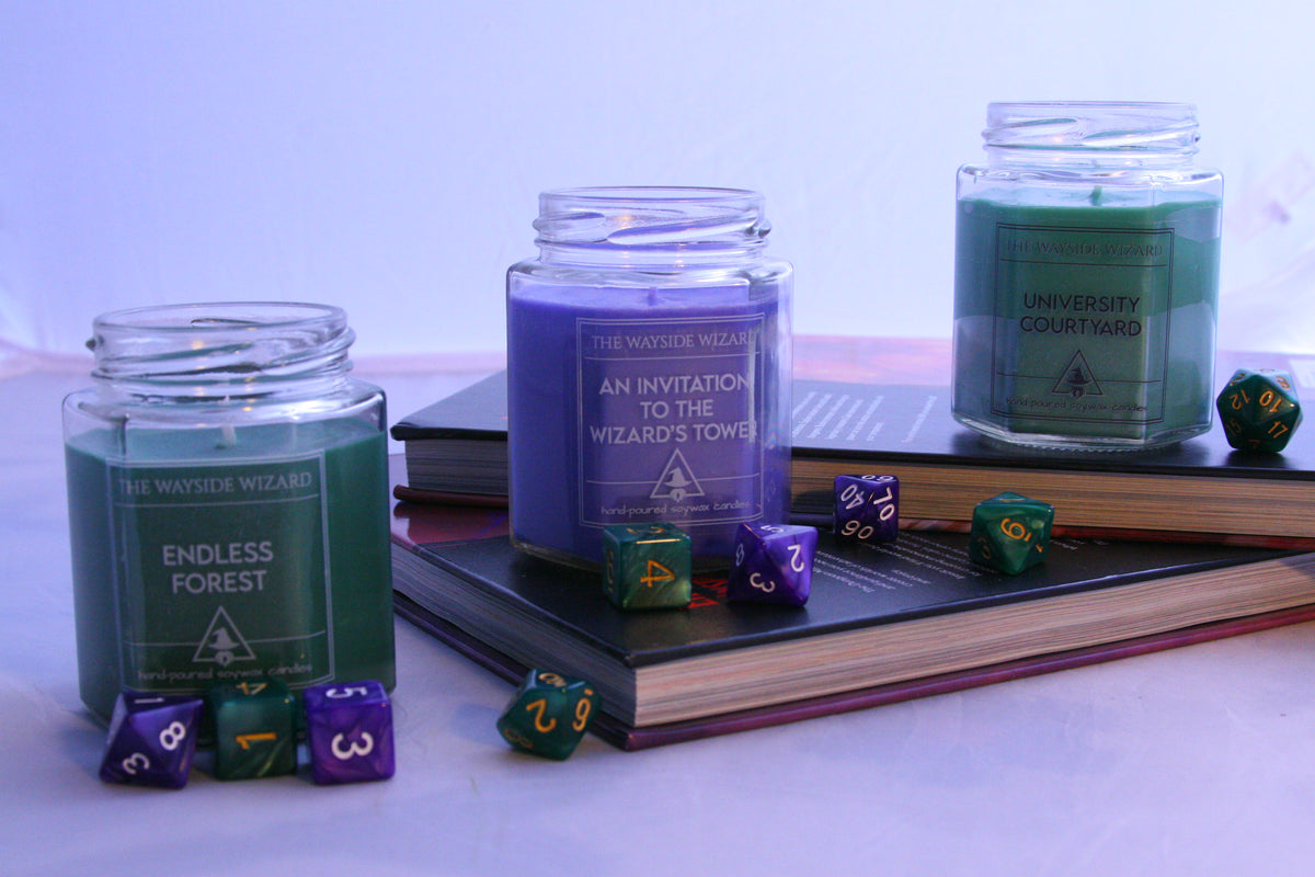 3 of the Wayside Wizard candles sitting up on dnd books with dice scattered around them. 