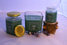 Load image into Gallery viewer, A collection of 3 wayside wizard candles. Some dice are scattered in front of them. One is a large cube container and the other two are hexagonal candles of varying sizes. The label on all of them is the same and reads: "The Wayside Wizard", "Endless Forest", "Hand-poured soywax candles". The small hexagonal candle sits ontop of a tree stump. The background is a white canvas